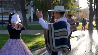 Geleneksel huaso kıyafetleri giymiş iki çiftin portresi şehir meydanındaki cueca ritmine alkış tutuyor.