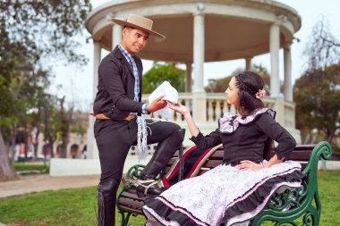 Geleneksel huaso kostümü giymiş genç bir çift meydanda kur yapıyor, Şili 'de ulusal bayramları kutluyorlar.