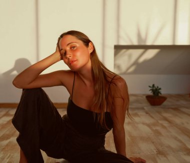 Güzel bir genç kadının portresi. Yoga stüdyosunda yerde rahatça oturuyor.