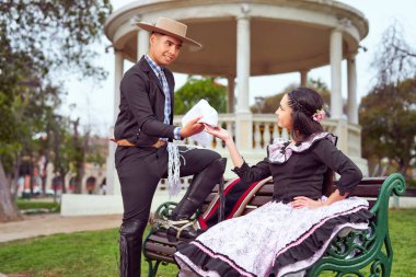 Geleneksel huaso kostümü giymiş genç bir çift meydanda kur yapıyor, Şili 'de ulusal bayramları kutluyorlar.