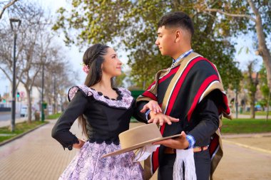 Şehir meydanında dans ederken birbirlerine bakan iki huasonun portresi.