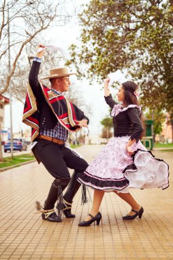 Şehir meydanında Şili Cueca dansı yapan bir çift huasonun portresi. 