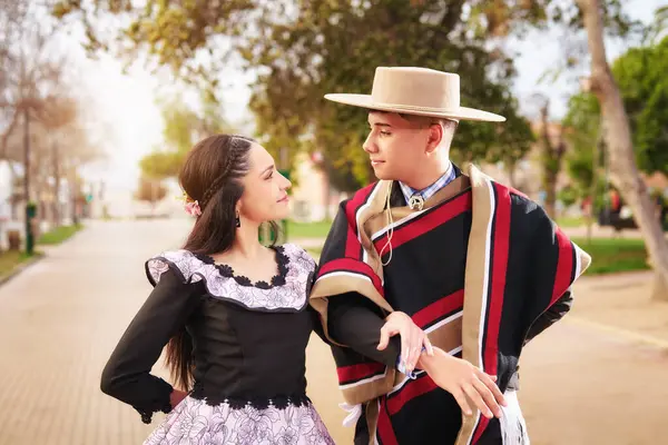  Genç Latin Amerikalı çift birbirlerine bakıyor. Meydanda huaso dansı yapmak için giyinmiş gülümsüyorlar.