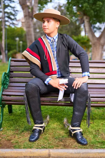 Şili Huaso kostümlü bir gencin portresi Şili 'nin Fiestas Patrias kutlamasında şehir meydanında oturuyor.