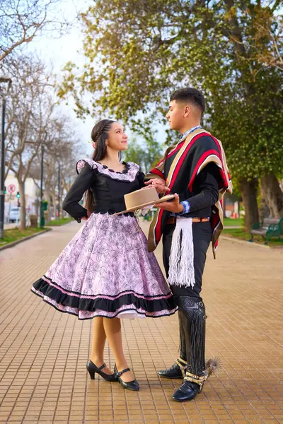 Şehir meydanında cueca dansı yaparken birbirlerine bakan iki huasonun portresi, Patricia 'ların kutlamaları. 