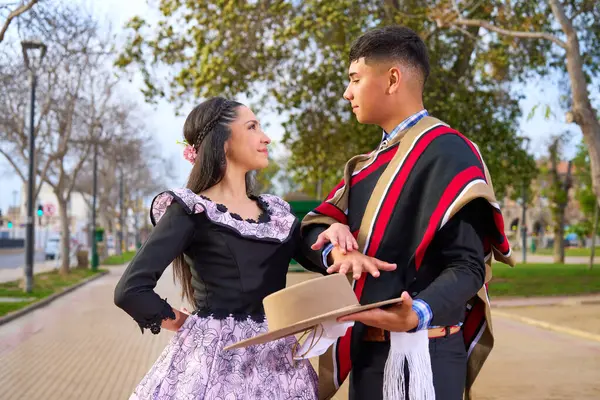 Şehir meydanında dans ederken birbirlerine bakan iki huasonun portresi.