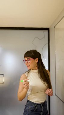 Beyaz tahta üzerine beyaz tahta kalemle yazı yazan genç beyaz iş kadını ya da öğretmen.