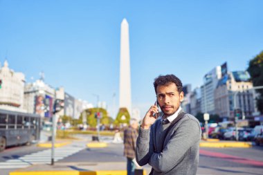 Latin Amerikalı iş adamı sokakta cep telefonuyla konuşuyor.