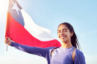 Güzel Latin bir kadının portresi. Mavi gökyüzüne karşı Şili bayrağı taşıyor.