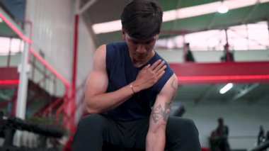 Spor salonunda dambılı kaldıran genç bir erkek atlet.