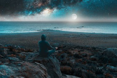 Tepenin tepesinde gece vakti Samanyolu 'yla meditasyon yapan ve kayan bir yıldızla...