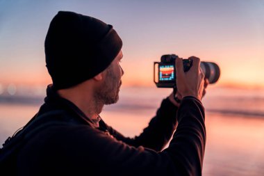 Fotoğrafçı gün batımında sahilde fotoğraf çekiyor. 