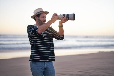 Olgun Latin adam deniz kıyısında fotoğraf çekiyor.