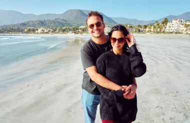 Güneşli bir günde güzel bir sahilde sarılan mutlu turistler.