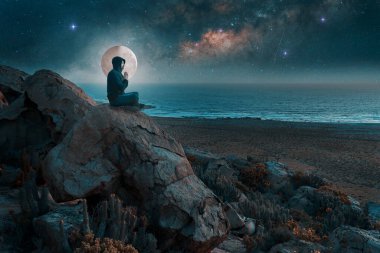 Gece bir tepede, Samanyolu ve gökyüzünde dolunayla meditasyon yapan bir insanın silüeti.