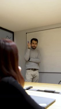 Genç işadamı beyaz tahta üzerine yazı ve açıklama yapıyor.