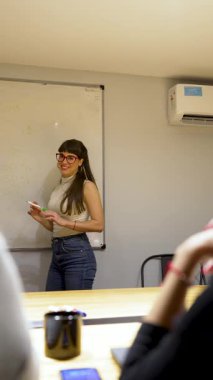 Beyaz tahta üzerine beyaz tahta kalemle yazı yazan genç beyaz iş kadını ya da öğretmen.