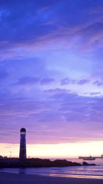 Sahile ve Şili 'nin kuzeyindeki Pasifik Okyanusu' nun üzerinde güzel renkli günbatımı olan deniz fenerine.