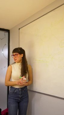 Beyaz tahta üzerine beyaz tahta kalemle yazı yazan genç beyaz iş kadını ya da öğretmen.