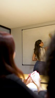 Beyaz tahta üzerine beyaz tahta kalemle yazı yazan genç beyaz iş kadını ya da öğretmen.