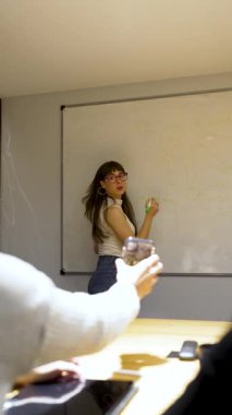 Beyaz tahta üzerine beyaz tahta kalemle yazı yazan genç beyaz iş kadını ya da öğretmen.