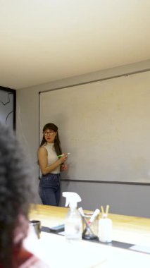 Beyaz tahta üzerine beyaz tahta kalemle yazı yazan genç beyaz iş kadını ya da öğretmen.