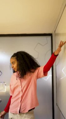 Beyaz tahta üzerine beyaz tahta kalemle yazı yazan Afrikalı Amerikalı iş kadını ya da öğretmen.