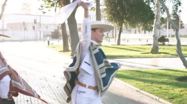 Şehir meydanında geleneksel huaso kıyafetleri içinde dans eden iki çiftin portresi.