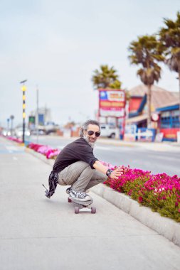 Bisikletle kaykay yapan ve eğlenen olgun bir adam.