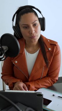 Latin kadın stüdyoda iş arkadaşını dinlerken podcast ses kaydı yapıyor.