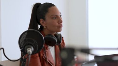 Latin kadın stüdyodaki birini dinlerken podcast ses kaydı yapıyor.