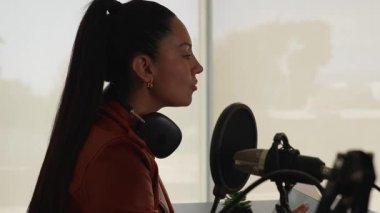 Latin kadın stüdyodaki birini dinlerken podcast ses kaydı yapıyor.