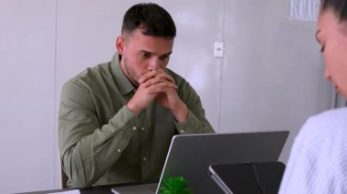 Genç endişeli adam ve bayan meslektaşı ofiste birlikte çalışıyorlar.