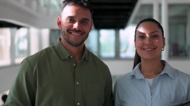 Ofiste birlikte poz verip gülümseyen iki yönetici. Elinde tablet olan kadın ve elinde not defteri tutan adam. 