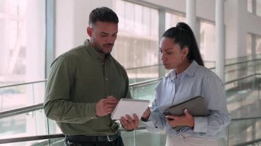 İki yönetici iş projesini tartışıyor ofiste duruyor ve notlar alıyor.