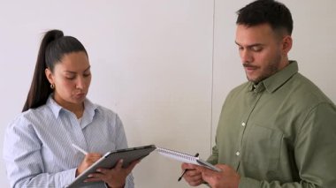 Genç iş çifti ofiste konuşuyor ve notlar alıyor.