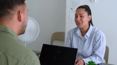 İki iş arkadaşı bir projeyi tartışıyor. Kadın ve erkek masanın önünde oturmuş birbirleriyle konuşuyor ve gülüyorlar. 