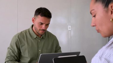 Genç endişeli adam ve bayan meslektaşı ofiste birlikte çalışıyorlar.