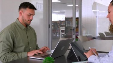 Genç endişeli adam ve bayan meslektaşı ofiste birlikte çalışıyorlar.