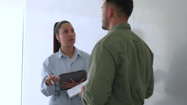 Genç iş çifti ofiste konuşuyor ve notlar alıyor.
