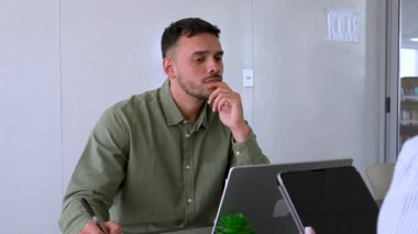 Genç endişeli adam ve bayan meslektaşı ofiste birlikte çalışıyorlar.