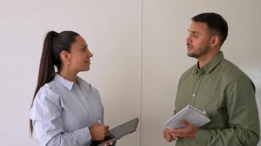 Genç iş çifti ofiste konuşuyor ve notlar alıyor.