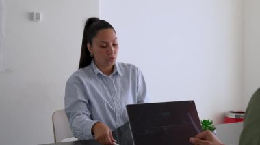 İki iş arkadaşı bir projeyi tartışıyor. Kadın ve erkek, masada oturmuş birbirlerinin önünde aletlerle iletişim kuruyorlar.