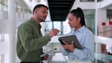 İki yönetici iş projesini tartışıyor ofiste birlikte yürüyor ve notlar alıyorlar.