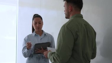 Genç iş çifti ofiste konuşuyor ve notlar alıyor.