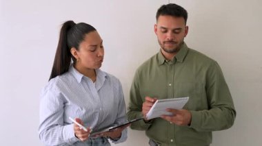 Genç iş çifti ofiste konuşuyor ve notlar alıyor.