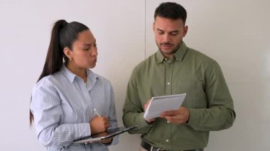 Genç iş çifti ofiste konuşuyor ve notlar alıyor.