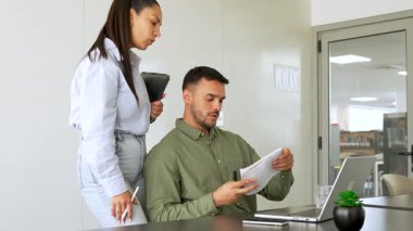 İki iş arkadaşı bir projeyi tartışıyor, fikirleri paylaşıyor, defterlere bakıyor.