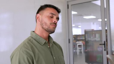 Genç, yorgun adam masada oturuyor ve ofiste geriniyor.