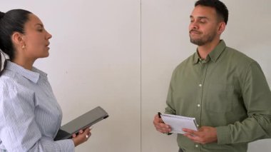 Genç iş çifti ofiste konuşuyor ve notlar alıyor.